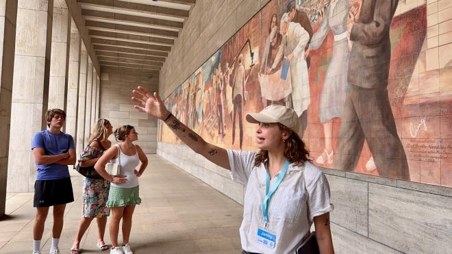 A tour guide in front of a mural