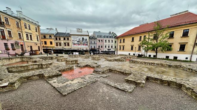 &ldquo;stone foundations of a large building with a cityscape in the background&rdquo;